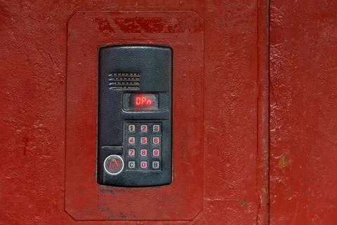 An intercom on old painted red steel surface with a keypad, digital display and Stock Photos