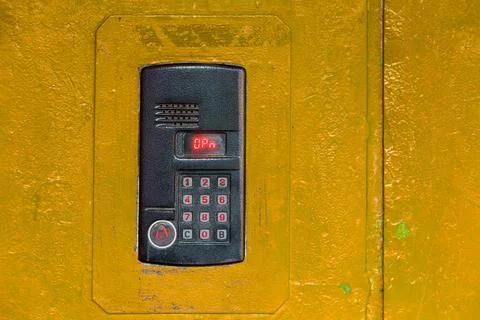 An intercom on old painted yellow steel surface with a keypad, digital display Фото