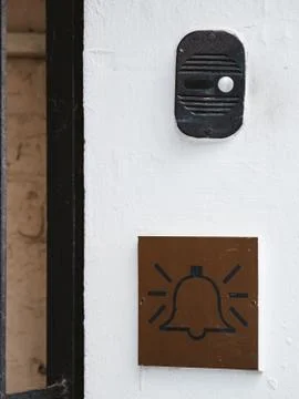 The intercom on the white wall of the house and the emblem with a bell icon.  Stock Photos