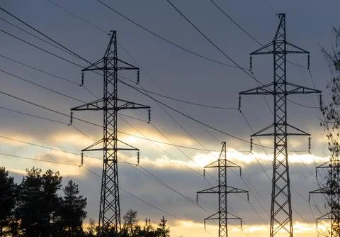 Interconnected Web of Electrical Towers Against a Sunset Sky Stock Photos