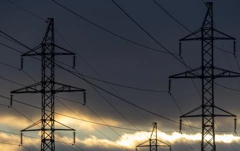 Interconnected Web of Electrical Towers Against a Sunset Sky Stock Photos