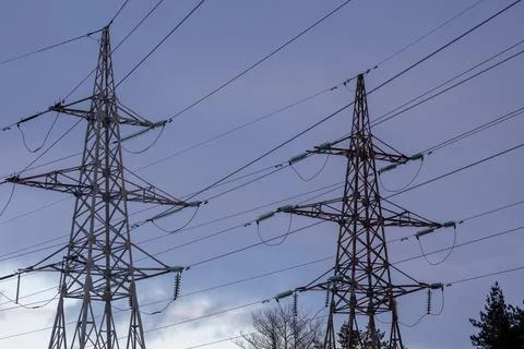 Interconnected Web of Electrical Towers Against a Sunset Sky Foto stock