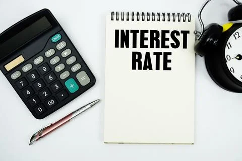 Interest Rate text written on notepad with calculator and alarm clock Stock Photos