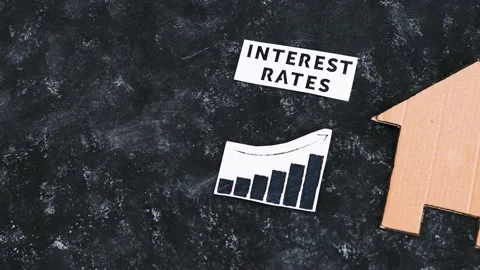 Interest rates text and graph showing cost of financing going up next to hous Stock Footage 203924379