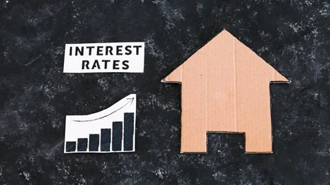 Interest rates text and graph showing cost of financing going up next to hous Stock Footage 203924425