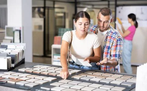 Interested couple browsing tile samples on display board in store Stock Photos