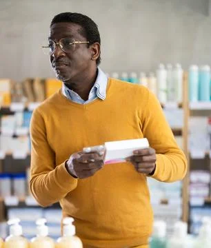 Interested customer browsing box of prescribed pills in pharmacy Stock Photos