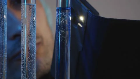 Interested eyes observe the diffusion of dissimilar liquids in test tubes in the Stock Footage 233031040