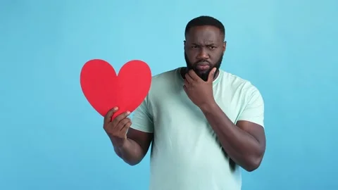 Interested guy hold red heart touch hand chin isolated blue color background Stock Footage 167691377