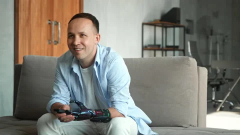 Interested guy with limb prothesis switches channels Stock Footage 157348592