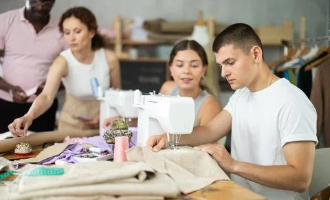 Interested guy working at machine during group sewing course for adults 스톡 사진