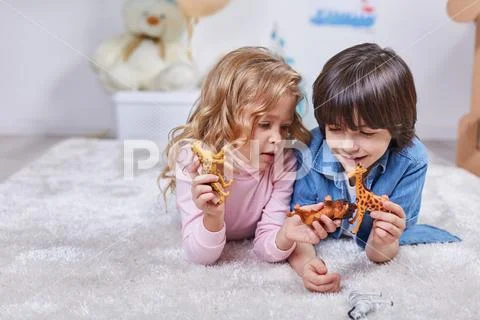 Interested little children toying with figures safari animals Stock Photos