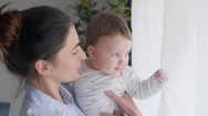 Interested Mother And Baby Girl Looking Through Window Stock Footage