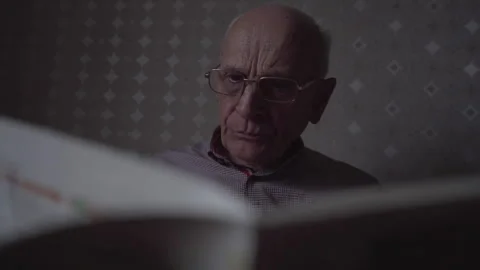 Interested old man in glasses for vision reads newspaper Stock Footage 243646407