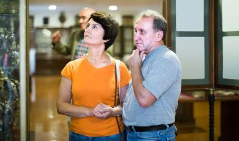 Interested senior couple examining objects applied art in museum Stockfoto's