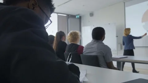 Interested student taking notes in a lecture in university classroom Stock Footage 69932894