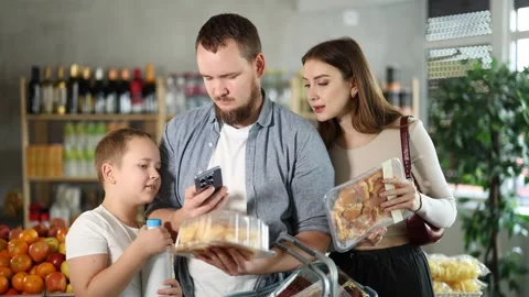 Interested tween boy with friendly young father and mother scanning barcodes on Stock Footage 314762634