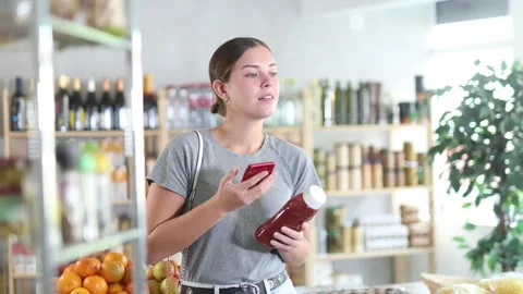 Interested woman scans the qr code of a ketchup package in a supermarket. Stock Footage 315025939