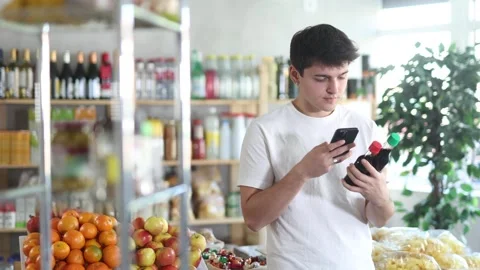 Interested young guy choosing traditional Chinese soy sauce in grocery store Stock Footage 321722699