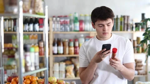 Interested young guy scanning QR code on bottle of red pepper powder to access Stock Footage 343164193