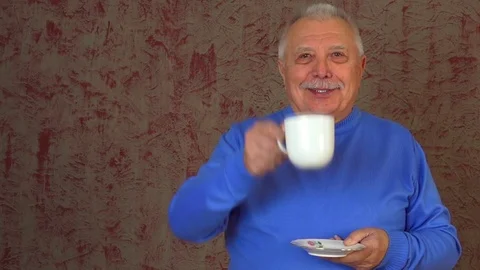 Interesting elderly man clinks cup drinks coffee and smiles Stock Footage 108605070