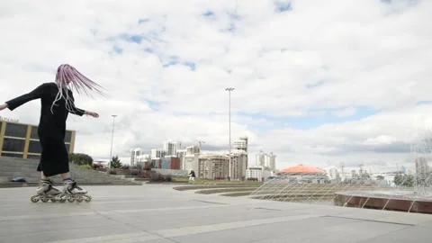 An interesting girl performs tricks on roller skates near the city fountain Stock Footage 147705041