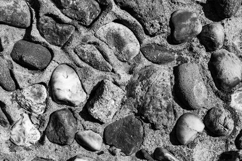 Interesting patterns created by smooth stones on sandy ground during daylight Stock Photos