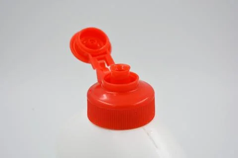 An interesting white plastic bottle with a red lid, an unusual package. Stock Photos