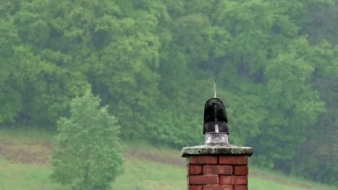 Interestingly shaped black object on top of a chimney in the rain Stock Footage 76783271