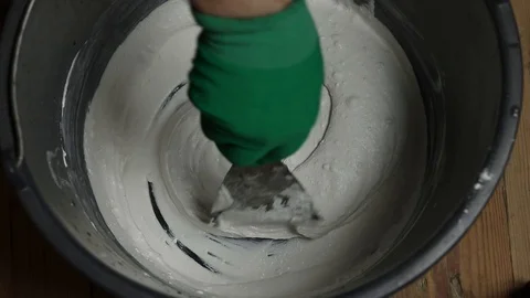 Interfere with putty in a bucket. stir the mortar by hand in a bucket. Stock Footage 129696582