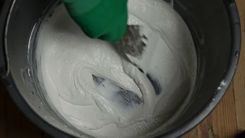 Interfere with putty in a bucket. stir the mortar by hand in a bucket. Stock Footage 129696713