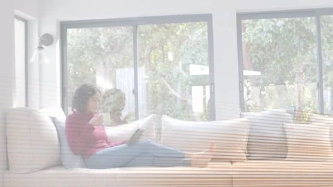 Interference clearing, woman sitting on sofa, reading tablet and sipping mug, Stock Footage 333396863