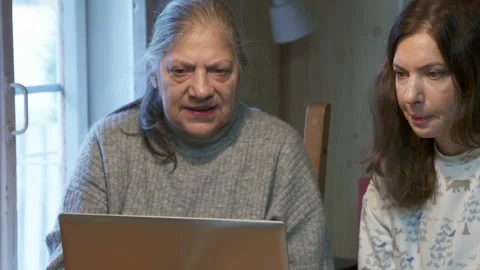 Intergenerational Learning: Mother and Daughter Focused on Laptop at Table Stock Footage 321147931