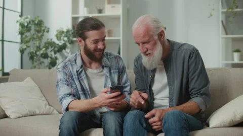Intergenerational technology lesson young adult shows older man tablet functions Stock Footage 262109403