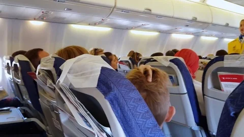 Interior of airplane cabin with passengers on seats. In-flight safety briefing. Stock Footage