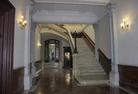 Interior of an ancient building with stone steps, columns, lamps on the walls. Stock Photos