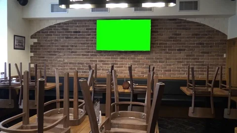 The interior of a bar with a TV green screen on a wall - chairs on tables Vídeo Stock 82683165