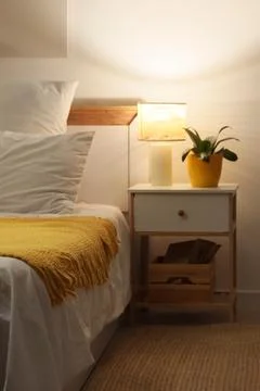 Interior of bedroom with table and glowing lamp at night Stock Photos