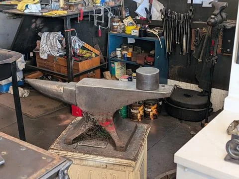 Interior of blacksmith shop featuring anvil, tools, and worktable Stock Photos