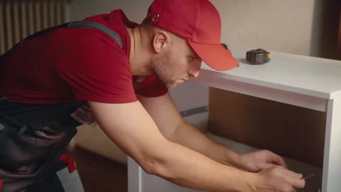 Interior carpenter measures and assembles furniture in a bright home environment Stock Footage 294913055