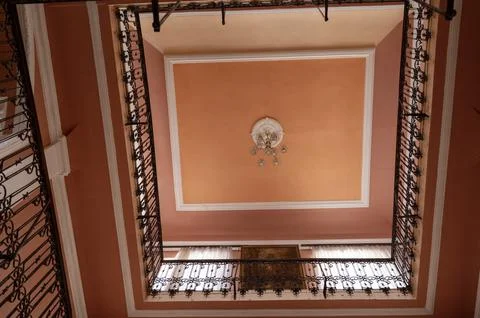 Interior ceiling view with arched windows and iron railings. Detailed Stock Photos