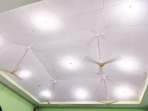 Interior ceiling view with multiple ceiling fans and bright LED lights in a gree Stock Photos