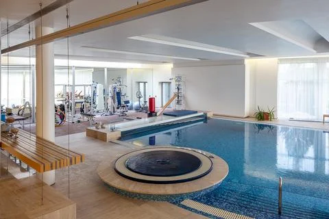Interior of comfortable mansion with training room, indoor pool and jacuzzi Stock Photos