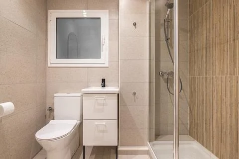Interior of compact bathroom with beige marble tiles. Toilet next to the Фото
