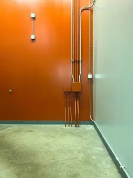 Interior corner with orange wall and electrical pipes Stock Photos