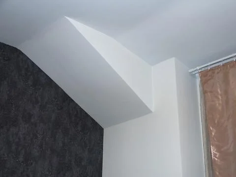 Interior corner with sloped ceiling and textured wall. Stock Photos