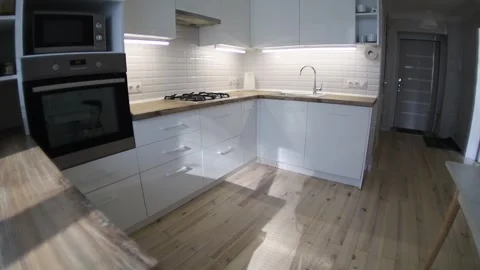 Interior of a cozy modern kitchen with white furniture and wooden parquet Video stock 305657553