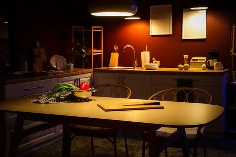 Interior of dark kitchen with counters, dining table and glowing lamps Stock Photos