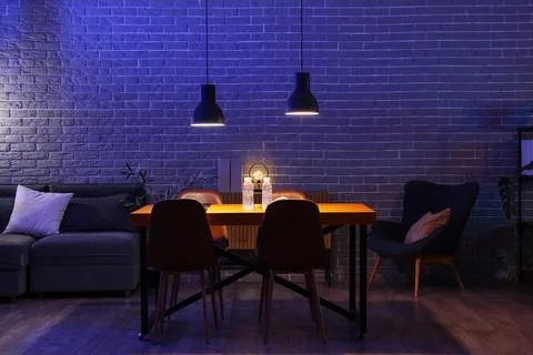 Interior of dark office with table, sofa and glowing lamps at night Stock Photos