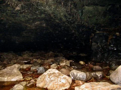 The Interior Of A Dark Welsh Cave With A River Flowing Through It Stock Photos